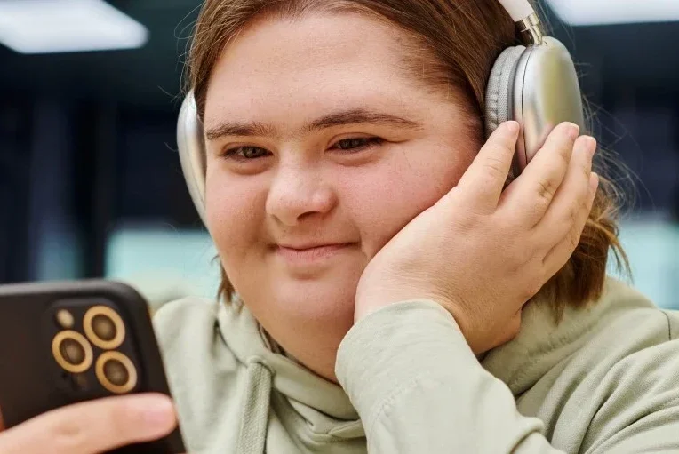 Disabled woman with down syndrome looking at phone and smiling